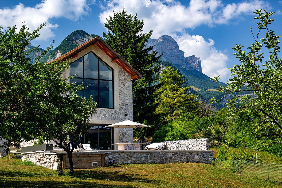 La-grange-des-alpes3 Maison en pierre de style chalet alpin avec grande baie vitrée donnant sur une terrasse et une piscine protégée par une couverture Coverseal.