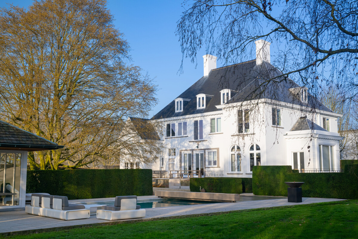 Maison en pierre de style chalet alpin avec grande baie vitrée donnant sur une terrasse et une piscine protégée par une couverture Coverseal.