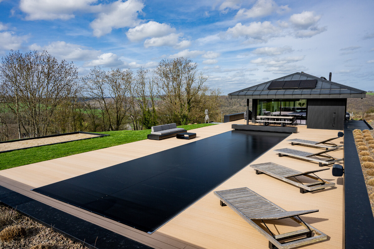 Maison en pierre de style chalet alpin avec grande baie vitrée donnant sur une terrasse et une piscine protégée par une couverture Coverseal.