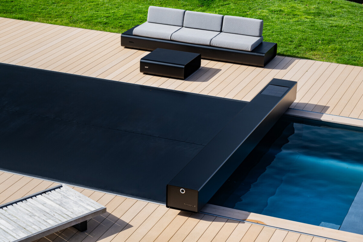 Maison en pierre de style chalet alpin avec grande baie vitrée donnant sur une terrasse et une piscine protégée par une couverture Coverseal.