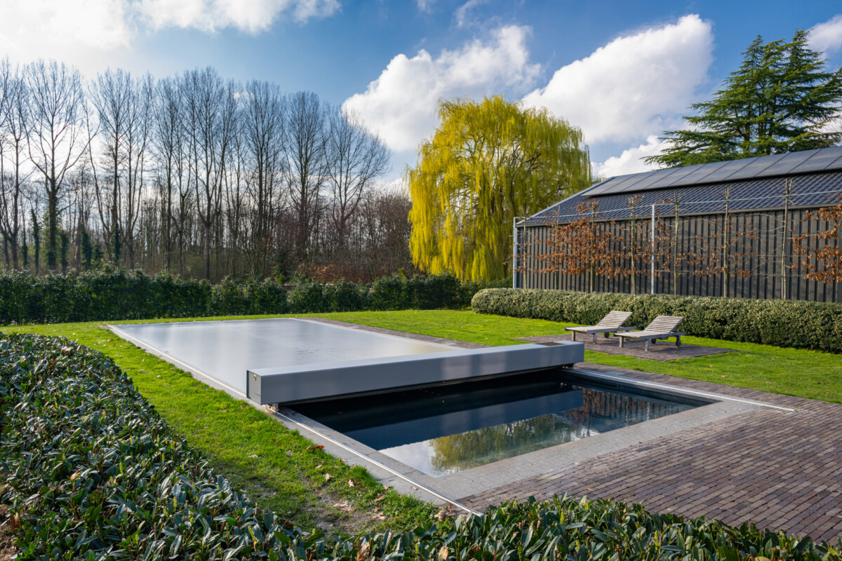 Maison en pierre de style chalet alpin avec grande baie vitrée donnant sur une terrasse et une piscine protégée par une couverture Coverseal.