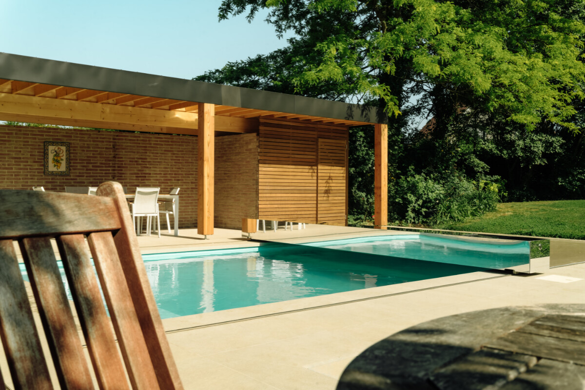 Maison en pierre de style chalet alpin avec grande baie vitrée donnant sur une terrasse et une piscine protégée par une couverture Coverseal.